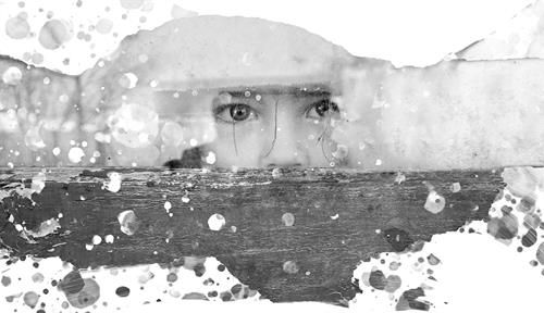 The eyes of a child are seen looking fearfully through a window.