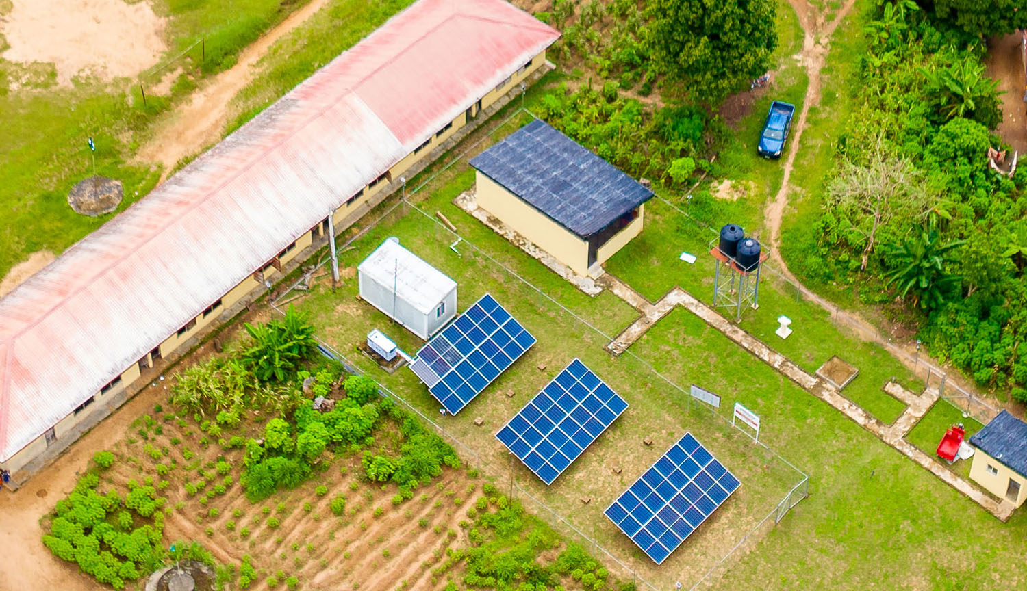 Aerial photograph of solar panels and sundry huts set among vegetation.
