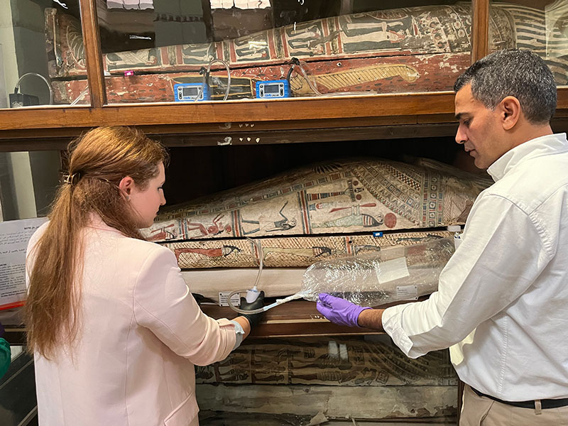 Two researchers collect air samples from an Egyptian mummy.