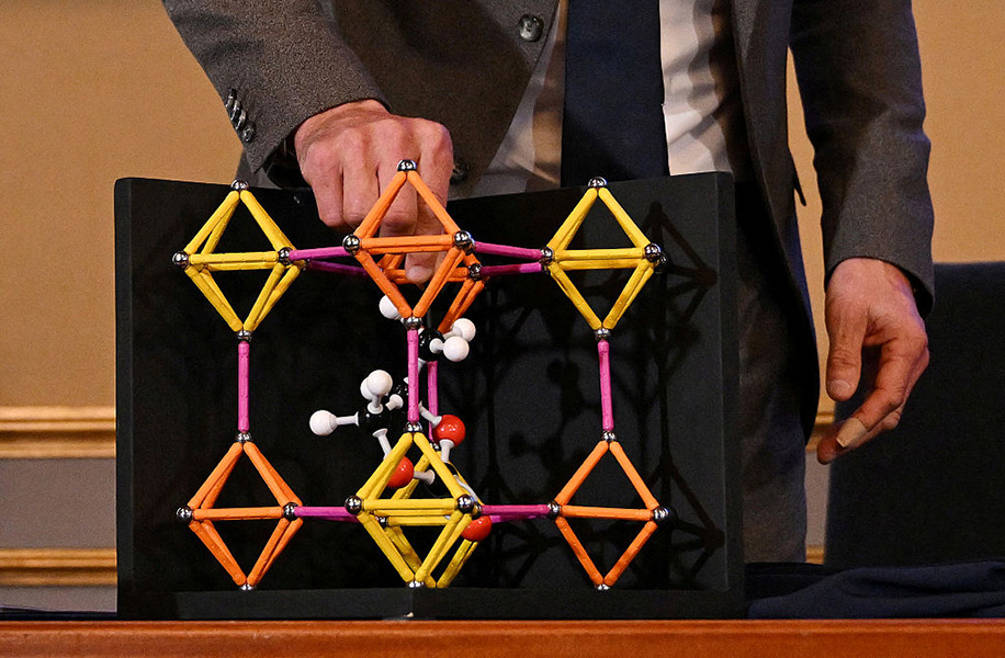 A plastic molecular model shows a lattice of crystals linked by organic molecules.